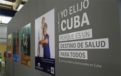 Cuatro carteles relacionados con la salud en una pared gris con texto que dice, Yo elijo Cuba porque es un destino de salud para todos.