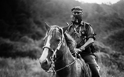 Un hombre con un pasamontañas montado en un caballo.