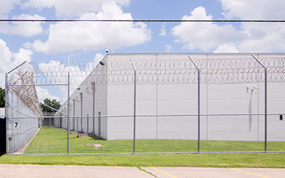 Un centro de detención con paredes blancas rodeado de una cerca de alambre.