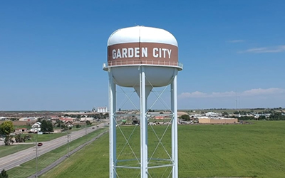 Una torre de agua que dice “Garden City Kansas” con la ciudad en el fondo.