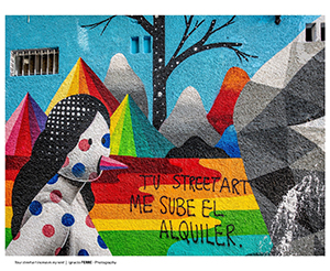 La pared de un edificio en Madrid tiene una pintura abstracta de una mujer y unas montañas con un letrero que lee: “TU STREETART ME SUBE EL ALQUILER.”