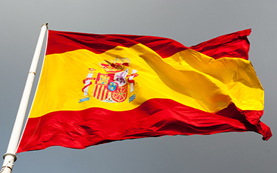La bandera española colgada del asta. Tiene dos franjas rojas, una arriba y una abajo y una franja amarilla en el centro con el escudo.