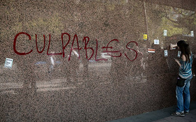 Una pared que dice, “culpables” en rojo en letra mayúscula. 