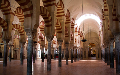 El interior de la Mezquita de Córdoba llena de arcos con rayas rojas y blancas.