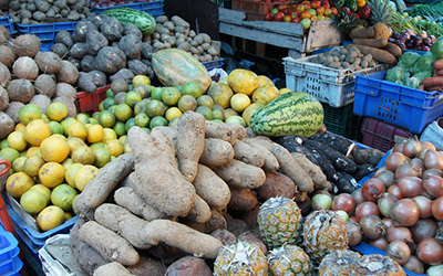 Un puesto de verduras y frutas que incluye papas, papayas y piñas.