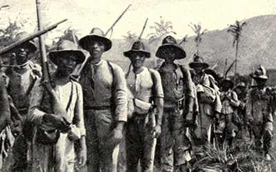 Campesinos en una fila en el campo cargando armas.