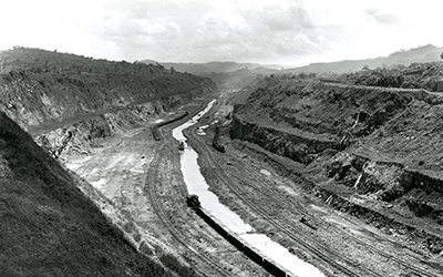 Una fotografia en blanco y negro que muestra la zona que sería el Canal de Panamá. Se ve un valle y un ferrocarril.