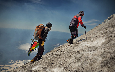 Dos personas con abrigos escalando una montaña.